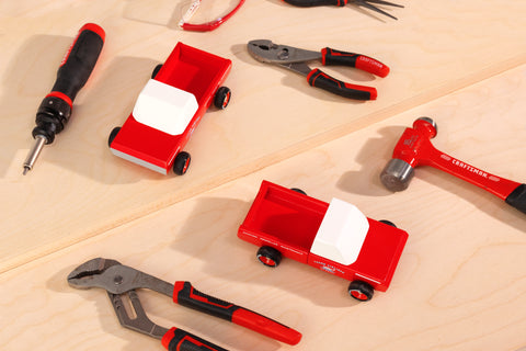 Två stycken röda leksaksbilar i trä från Candylab Toys. Pickupen klarar av att köra runt små leksaker.