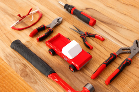 Pickup leksak bredvid hammare, tång och skyddsglasögon. Candylab Toys leksaker.